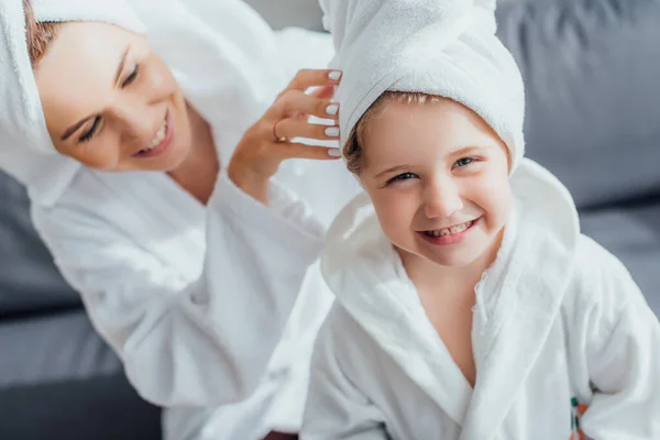 Selective focus of young woman touching towel on head of daughter, high angle view — Stock Photo