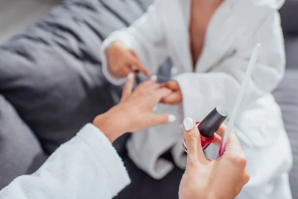 Visão cortada da criança fazendo manicure para mãe segurando esmalte e arquivo de unhas — Fotografia de Stock