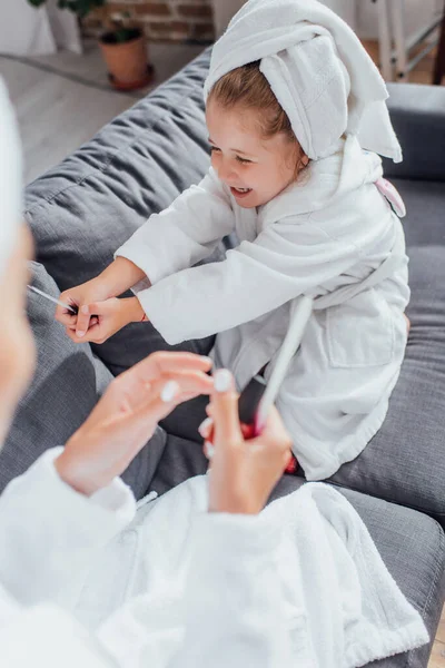 Vista ad alto angolo della ragazza che tiene la lima per unghie vicino alla madre che fa manicure — Foto stock