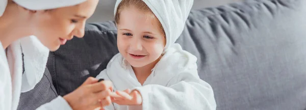 Вибірковий фокус мами, що робить манікюр доньці в білому халаті та рушнику на голові — стокове фото