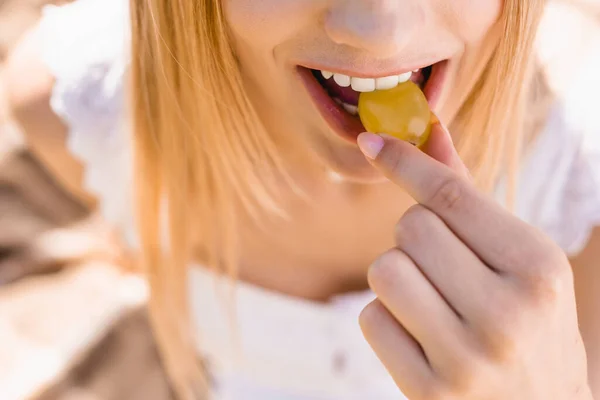 Vue partielle de jeune femme mangeant du raisin mûr, mise au point sélective — Photo de stock