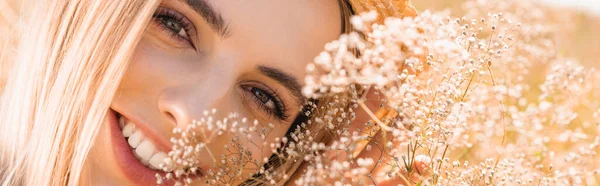 Retrato de mulher loira sensual olhando para a câmera perto de flores silvestres, imagem horizontal — Fotografia de Stock