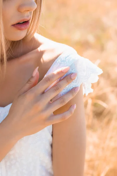 Ausgeschnittene Ansicht einer sinnlichen jungen Frau im Sommeroutfit, die bei Sonnenschein die Schulter berührt — Stockfoto