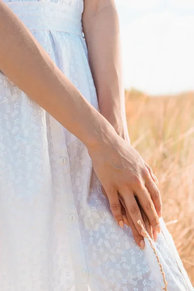 Vue partielle de la femme en robe d'été blanche debout dans la prairie — Photo de stock