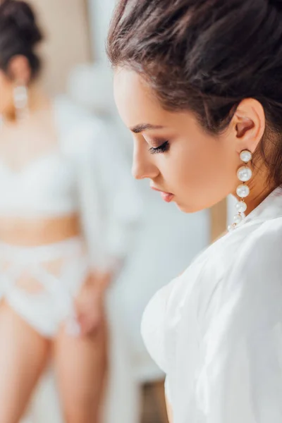 Selective focus of bride in pearl earring and silk robe at home — Stock Photo