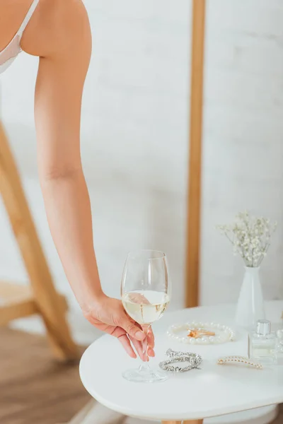 Vista recortada de la novia sosteniendo copa de vino cerca de accesorios en la mesa de café - foto de stock