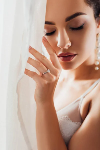 Selective focus of bride in bra touching white curtain — Stock Photo