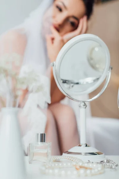 Selektiver Fokus auf Accessoires, Spiegel und Flasche Parfüm auf Couchtisch in der Nähe der Braut zu Hause — Stockfoto