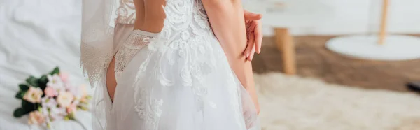 Colpo panoramico di sposa in mutandina e velo che indossa abito da sposa in camera da letto — Foto stock