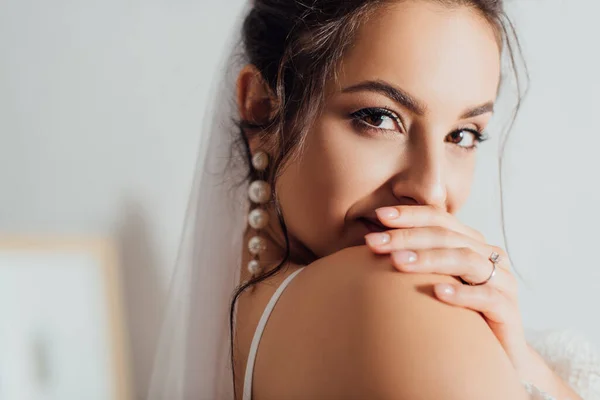 Selektiver Fokus der jungen Braut in Perlenohrring und Schleier, die in die Kamera blickt — Stockfoto