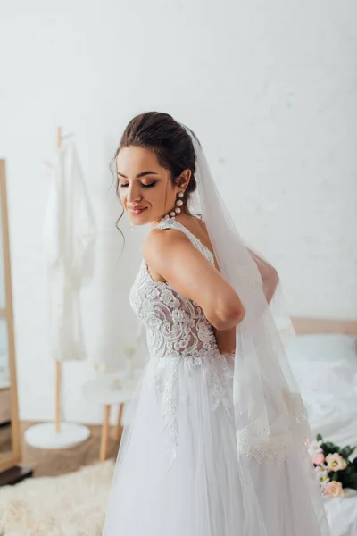 Noiva jovem em vestido de noiva branco e véu de renda em casa — Fotografia de Stock