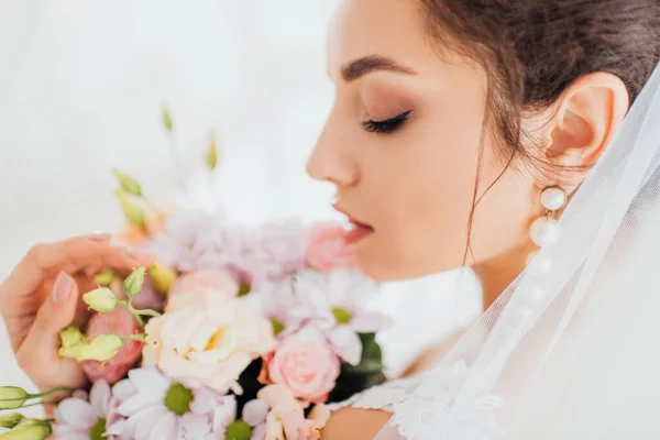 Selective focus of young bride in veil holding floral bouquet — Stock Photo