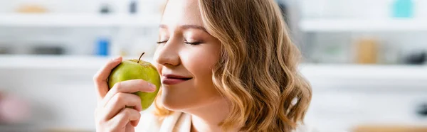 Panoramic crop of woman with closed eyes smelling apple — Stock Photo