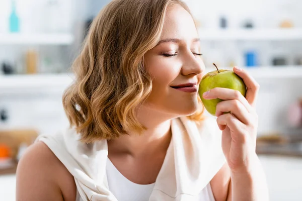 Молода жінка з закритими очима пахне зеленим яблуком — стокове фото