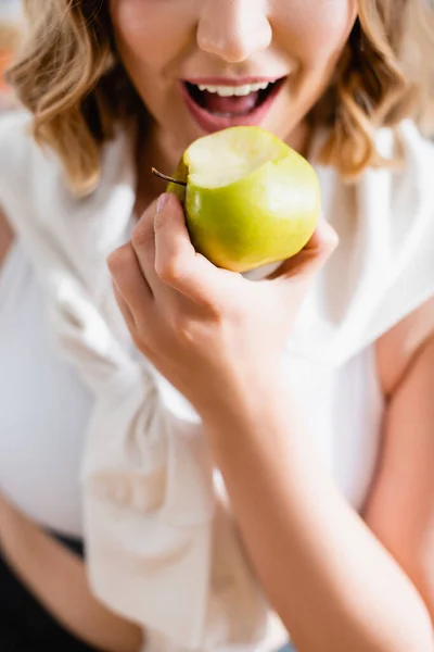 Cropped view of young woman eating green apple — Stock Photo