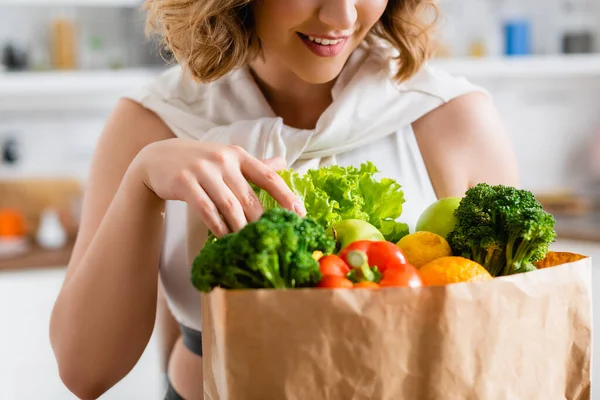 Обрезанный вид молодой женщины, трогающей продукты в бумажном пакете — стоковое фото