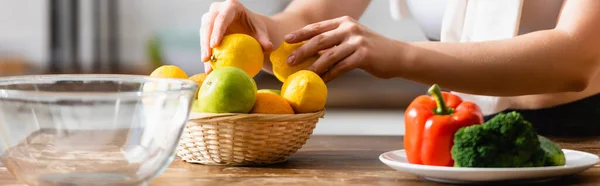 Encabezado del sitio web de la mujer tocando limones cerca de verduras en el plato - foto de stock