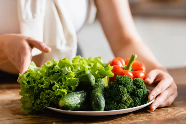 Messa a fuoco selettiva della donna toccando piatto con verdure — Foto stock