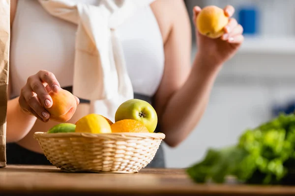 Vista cortada de mulher segurando frutas frescas na cozinha — Fotografia de Stock