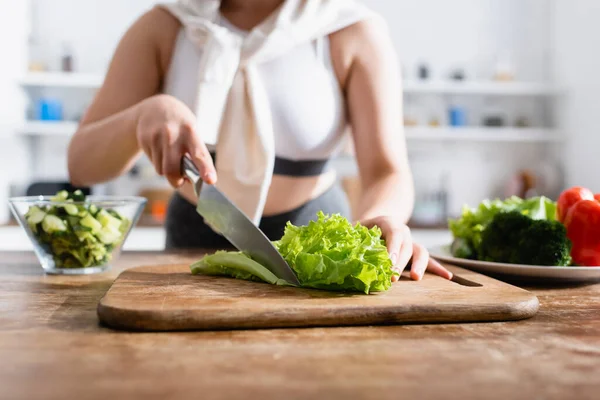 Cropped view of woman cutting fresh lettuce on chopping board — Stock Photo