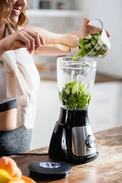 Abgeschnittene Ansicht einer Frau mit Schüssel mit frischem Salat und Gurken in der Nähe des Mixers — Stockfoto