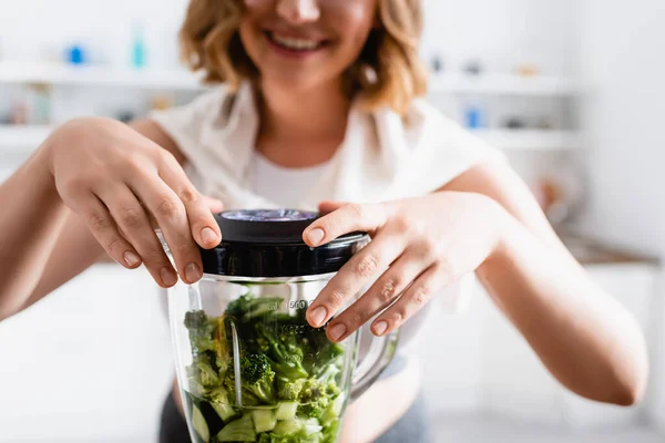 Abgeschnittene Ansicht von Frau berührt Mixer mit grünem Salat und Gurke — Stockfoto