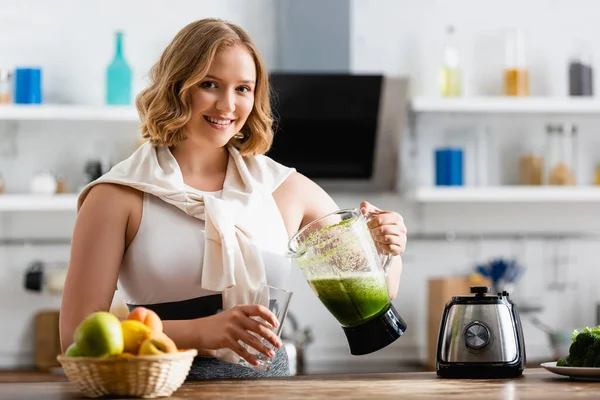 Foyer sélectif de jeune femme tenant mélangeur avec smoothie mélangé près du verre — Photo de stock