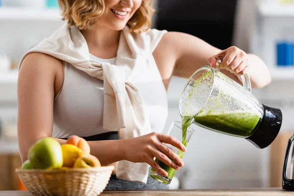 Visão parcial da jovem mulher derramando smoothie verde misto em vidro — Fotografia de Stock