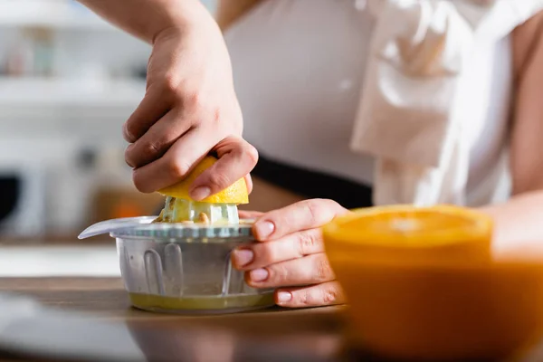 Close up de jovem mulher espremendo laranja enquanto prepara o suco — Fotografia de Stock