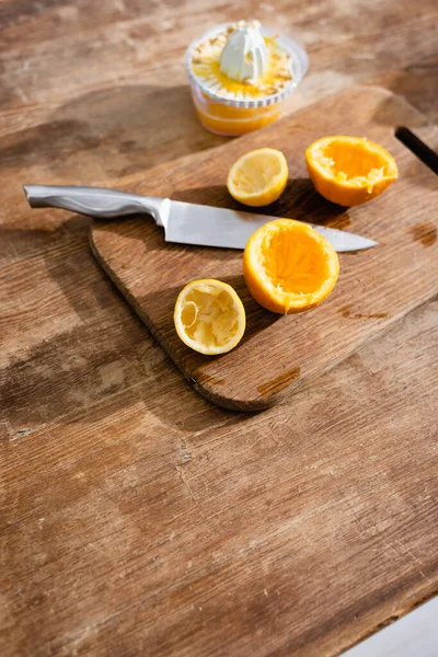 Visão de alto ângulo de metades de laranja espremidas perto da faca e do espremedor — Fotografia de Stock