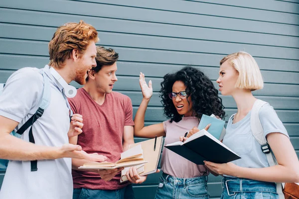 Angry african american student standing with raised hand near multicultural friends — Stock Photo