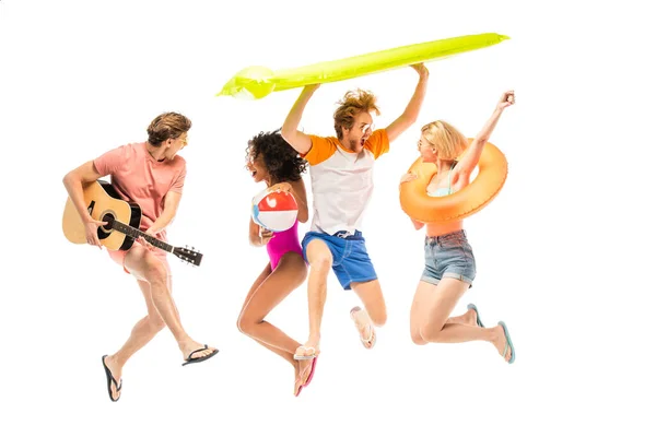 Amigos multiétnicos entusiasmados com guitarra acústica, colchão inflável e salto de bola isolado no branco — Fotografia de Stock