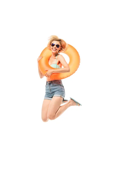 Woman in sunglasses and flip flops holding swim ring while jumping isolated on white — Stock Photo