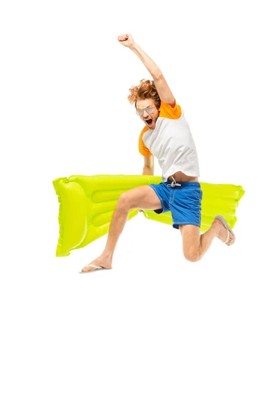 Excited man in sunglasses and flip flops holding inflatable mattress while jumping isolated on white — Stock Photo
