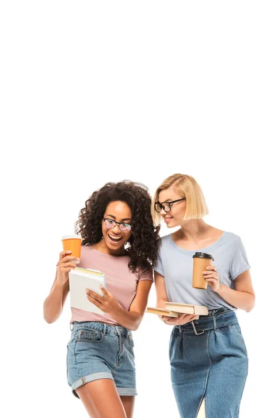 Estudiantes multiétnicos mirando el teléfono inteligente mientras sostienen el café para ir aislados en blanco - foto de stock