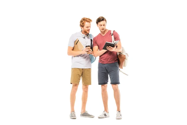 Des étudiants avec du café à emporter et des sacs à dos regardant un carnet isolé sur blanc — Photo de stock