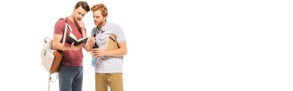 Foto panorámica de estudiantes reflexivos mirando cuaderno aislado en blanco - foto de stock