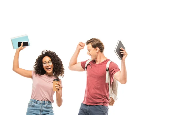 Multiethnic students with coffee to go, books and smartphone showing yeah gesture isolated on white — Stock Photo