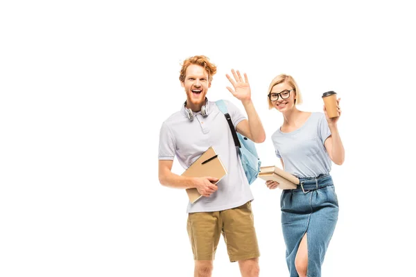 Students with books and coffee to go waving hand at camera isolated on white — Stock Photo