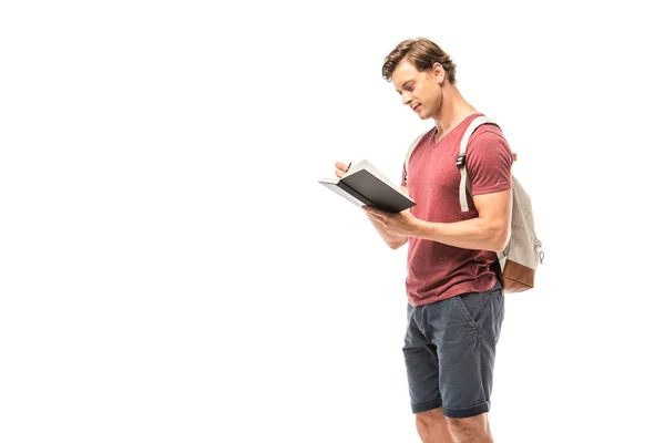 Student mit Rucksack schreibt auf Notizbuch isoliert auf weiß — Stockfoto