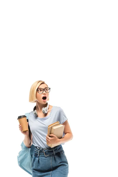 Schockierter Student mit Coffee to go und Büchern auf Weiß — Stockfoto