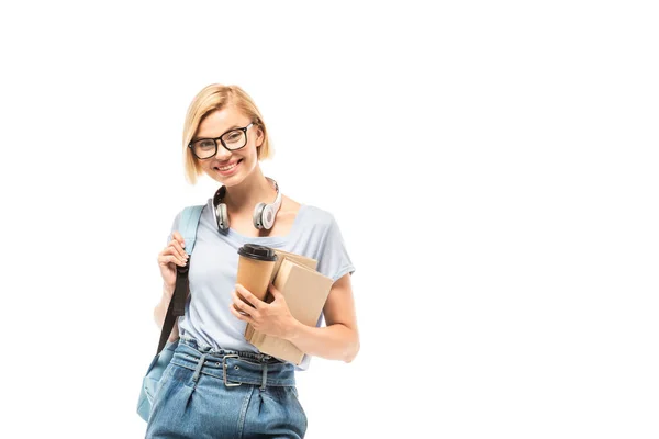 Student mit Rucksack blickt in die Kamera, während er Coffee to go in der Hand hält und Bücher isoliert auf weiß — Stockfoto