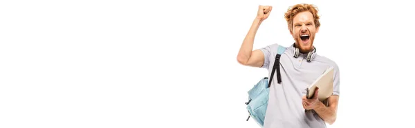 Horizontal crop of student holding notebook while showing yes gesture isolated on white — Stock Photo