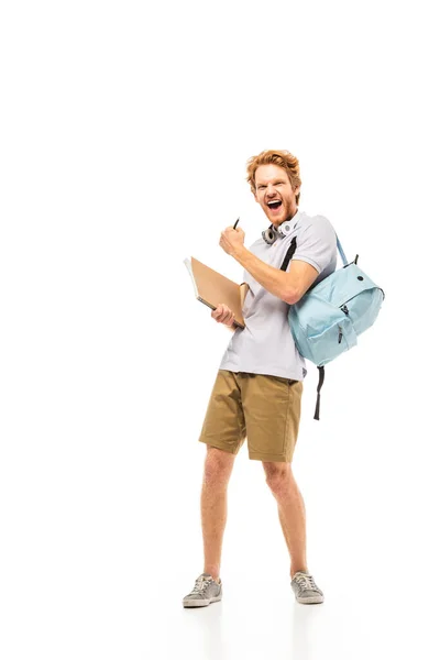 Student with backpack and notebook showing yeah gesture on white background — Stock Photo