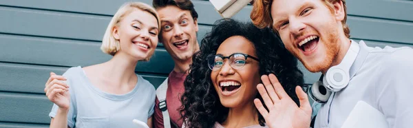 Prise de vue panoramique d'étudiants multiethniques regardant une caméra dans une rue urbaine — Photo de stock