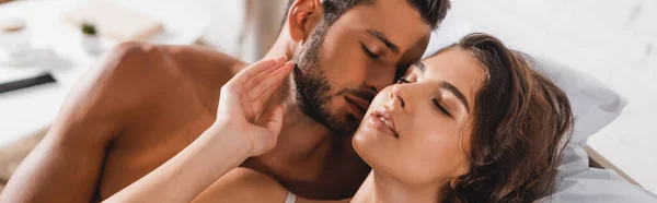 Horizontal crop of shirtless man kissing girlfriend on bed — Stock Photo