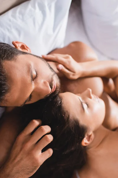 Overhead view of shirtless man touching hair of young woman on bed — Stock Photo