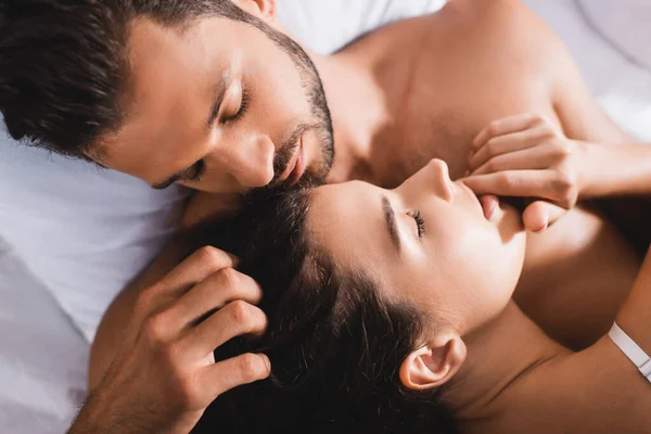 Draufsicht des bärtigen Mannes, der Haare einer brünetten Frau auf dem Bett berührt — Stockfoto