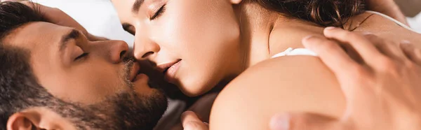 Панорамная концепция того, как мужчина целует молодую женщину в постели — стоковое фото