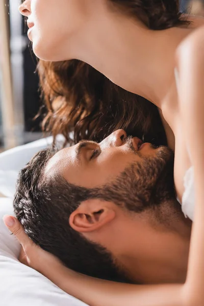 Selective focus of seductive woman embracing bearded man on bed — Stock Photo